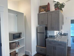 Una cocina moderna con gabinetes grises, un refrigerador de acero inoxidable, un microondas y un lavamanos.