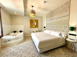 A hotel room with a large bed, a bathtub, a wall-mounted mirror, and a decorative wall panel. - Hotel Boutique Adealba Badajoz (Badajoz)