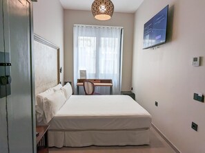 A hotel room with a bed, a desk, a chair, a television, and a window with curtains. - Hotel Boutique Adealba Badajoz (Badajoz)