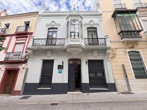 Un edificio con entrada central, balcones ornamentales y un letrero que indica un hotel.