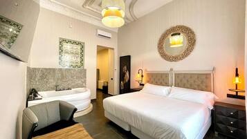 Habitación de hotel con una cama grande, una zona de estar, una bañera y un espejo en la pared.