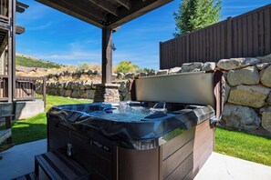 Een jacuzzi met een stenen muur en een houten omheining op de achtergrond.