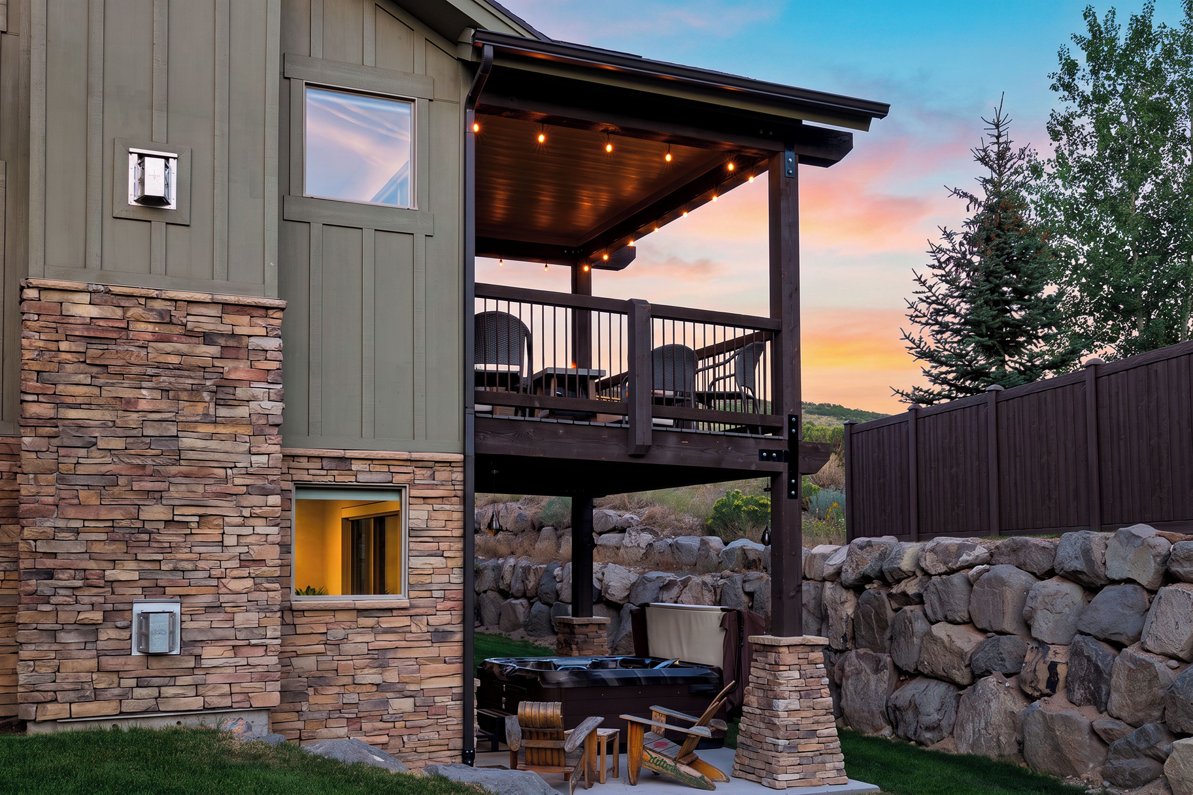 Une maison à deux étages avec une façade en pierre, un balcon agrémenté de mobilier d’extérieur et un jacuzzi.