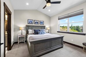 Een slaapkamer met een groot bed, twee nachtkastjes, een plafondventilator en een raam met uitzicht.