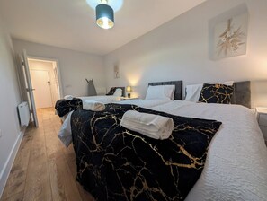 Et hotelværelse med en seng, et sengebord, en lampe og en dør.