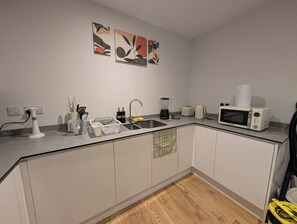 Una cocina moderna con un lavamanos, un microondas y un tostador. Hay pinturas abstractas en la pared.
