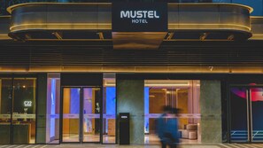 El exterior de un hotel con un cartel llamativo que dice 'MUSTEL HOTEL'.