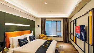 A hotel room with a bed, a television, a window with curtains, and a view of the city.