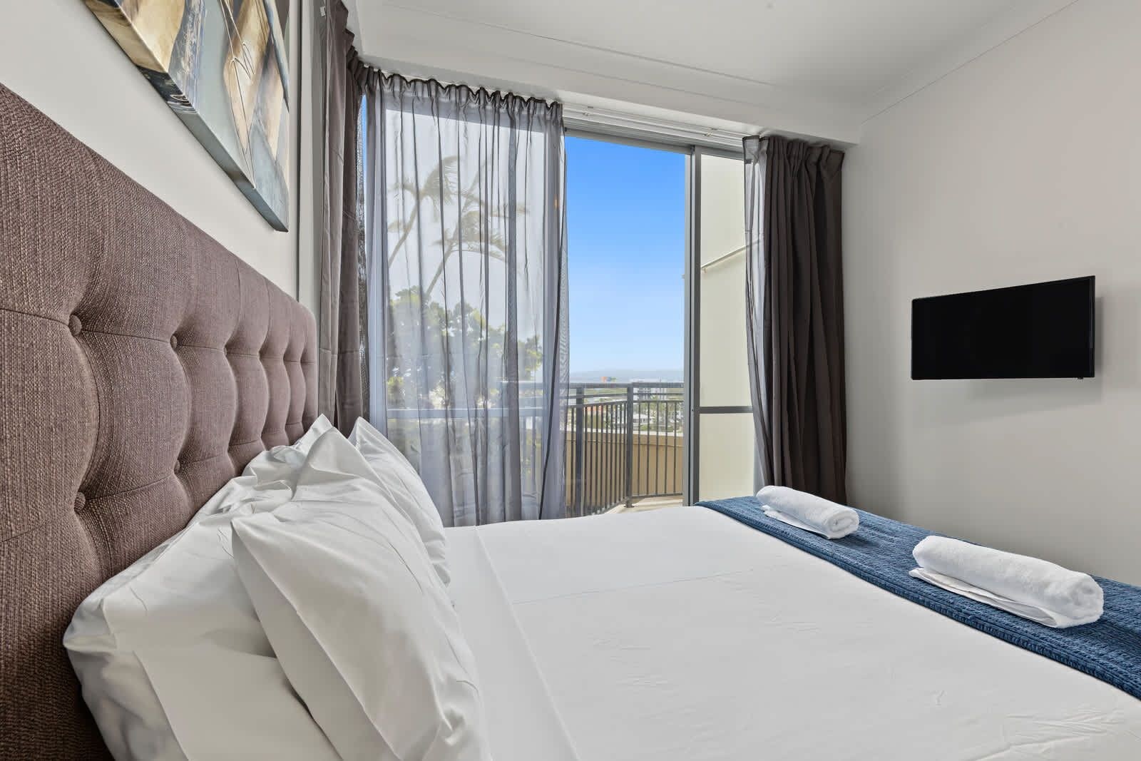 Une chambre d’hôtel dotée d’un grand lit, d’un téléviseur à écran plat et d’un balcon avec des rideaux.