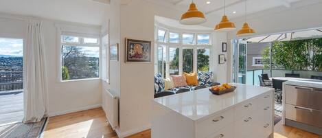A modern kitchen with a central island, pendant lighting, and a view of the outdoors.