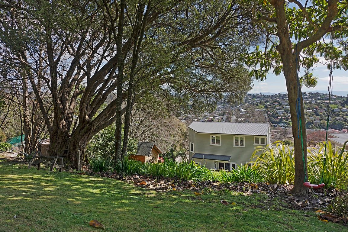 A residential property with a large tree, a house, and a view of a town.