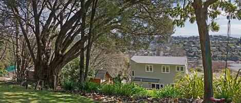 A residential property with a large tree, a house, and a view of a town.