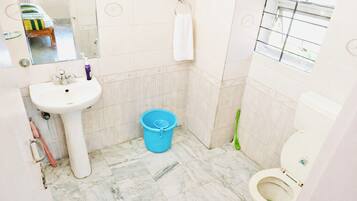 A bathroom with a sink, toilet, and a blue bucket.