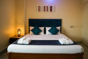 A neatly made bed with a headboard, two pillows, and a bedside lamp. - Rooftop Cityscape Inn || Luxurious 3BHK Apartment || Cityview (Guwahati)