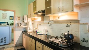 A kitchen with a gas stove, cabinets, and a refrigerator. - Rooftop Cityscape Inn || Luxurious 3BHK Apartment || Cityview (Guwahati)