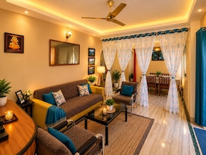 A living room with a sofa, armchairs, a coffee table, and a dining area with a table and chairs. - Rooftop Cityscape Inn || Luxurious 3BHK Apartment || Cityview (Guwahati)