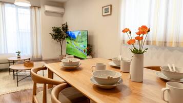 A dining area with a wooden table, bowls, cups, and a vase with flowers.