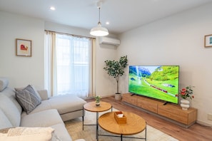 A modern living room with a sofa, a television, a small table, and a potted plant. - Nikyo Yume DreamCat Villa Osaka (Osaka)
