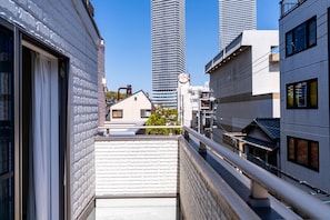 A narrow balcony with a view of modern buildings and a traditional house in the background. - Nikyo Yume DreamCat Villa Osaka (Osaka)
