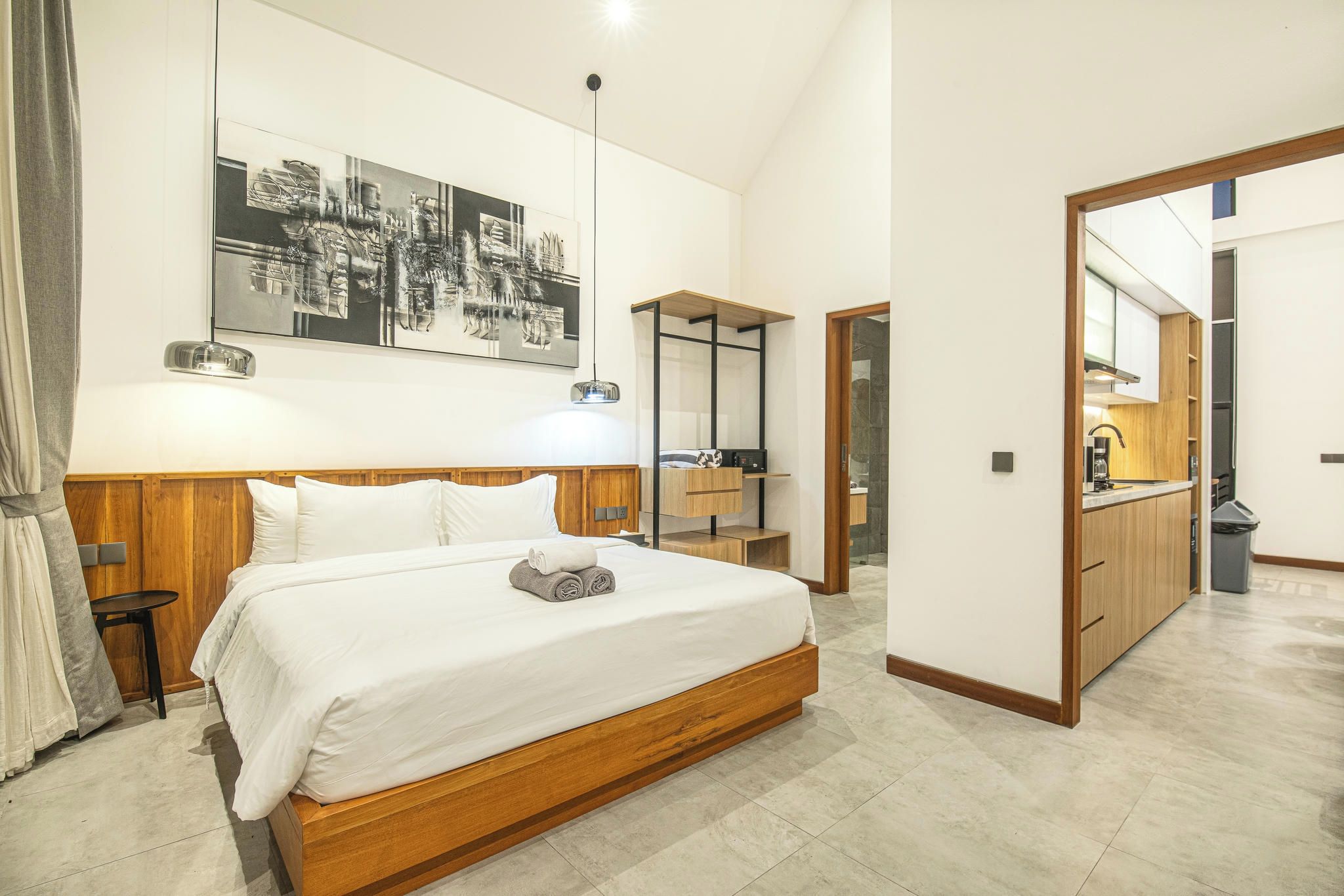 Un dormitorio moderno con una cama grande, mesitas de noche, una lámpara de pared y una obra de arte con vista a la ciudad.