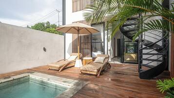 A poolside area with wooden decking, lounge chairs, and a spiral staircase.