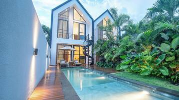 A modern house with a pool, surrounded by lush greenery.