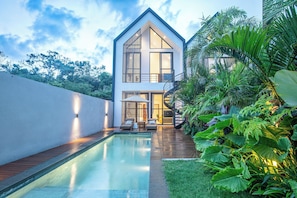 A modern house with a swimming pool, outdoor seating, and lush greenery. - 2BR Ocean View Pool Villa in Nusa Dua (Nusa Dua)