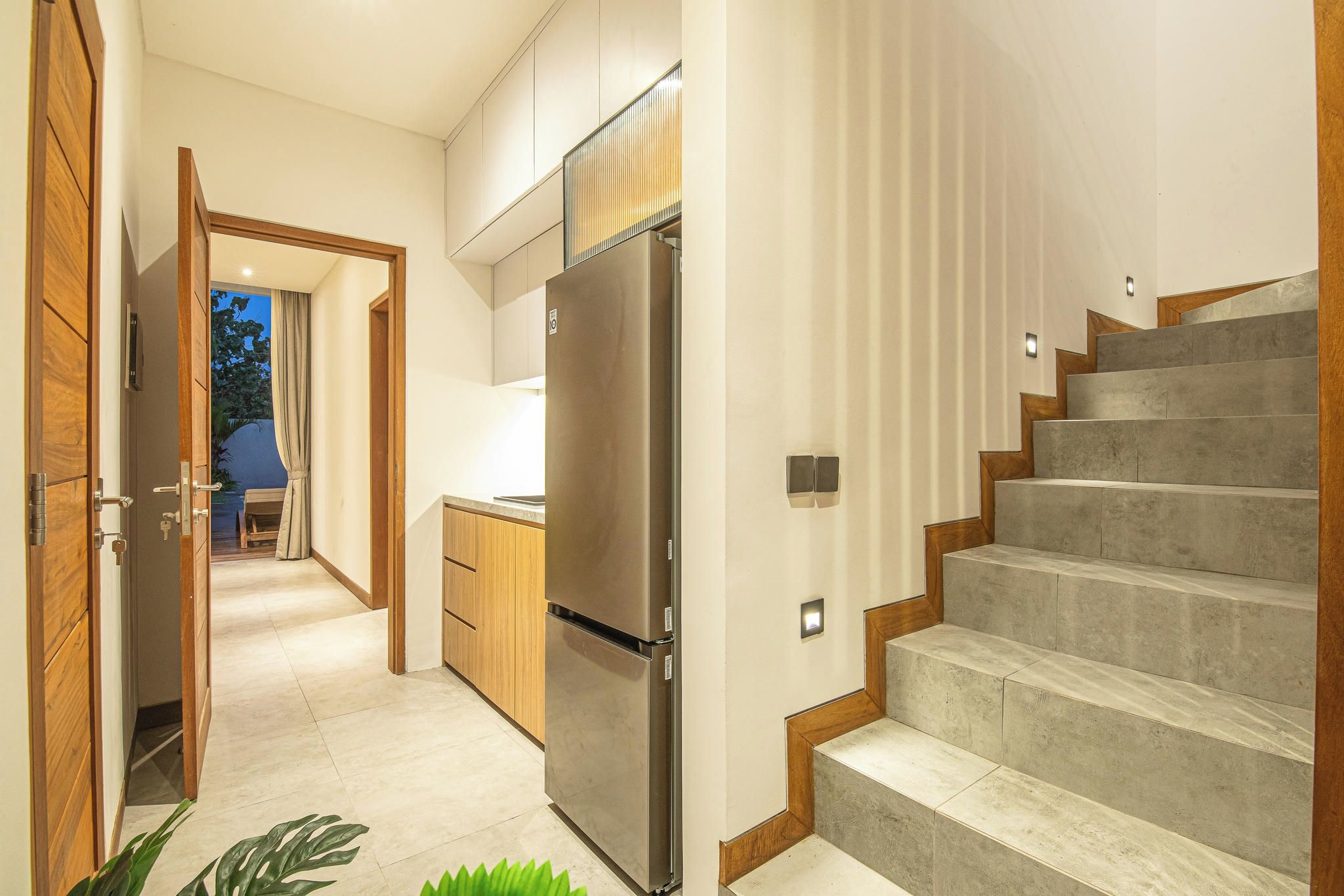 A modern kitchen with a stainless steel refrigerator, wooden cabinets, and a built-in oven.