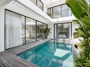 A modern house with a glass-enclosed patio, a swimming pool, and a bedroom with a large window. - Casa Rio 3BR Enclosed Living & Pool (Keroboken Kelod)
