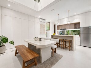 A modern kitchen with a central island, bar stools, a built-in refrigerator, and pendant lighting. - Casa Rio 3BR Enclosed Living & Pool (Keroboken Kelod)