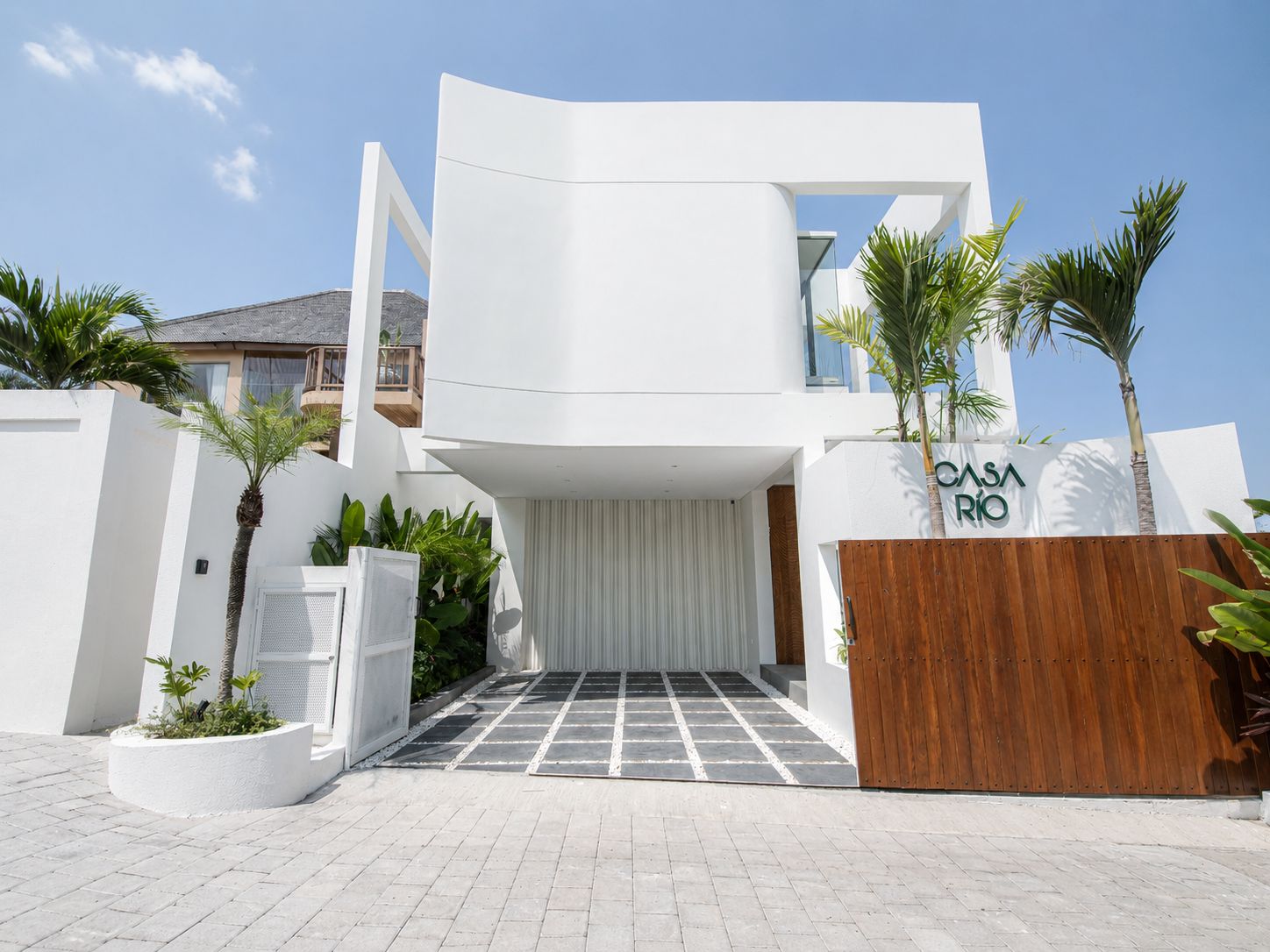 Un edificio moderno con fachada blanca, una reja de madera y un cartel que dice 'CASA RIO'.