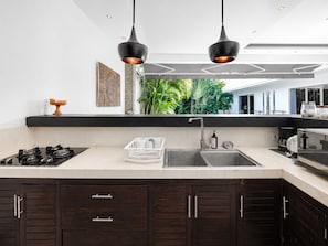 A modern kitchen with a gas stove, a sink, and two pendant lights. - Villa Juna Serene 3BR Hideaway Seminyak (Seminyak)