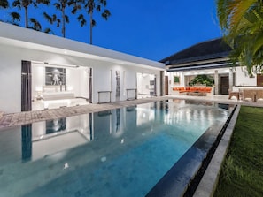 Una casa moderna con piscina, un espacio de sala con sofá y un comedor.