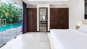 Ein modernes Schlafzimmer mit einem großen Bett, einem Holzschrank, einem Badezimmer mit Spiegel und einer Glastür zum Pool.