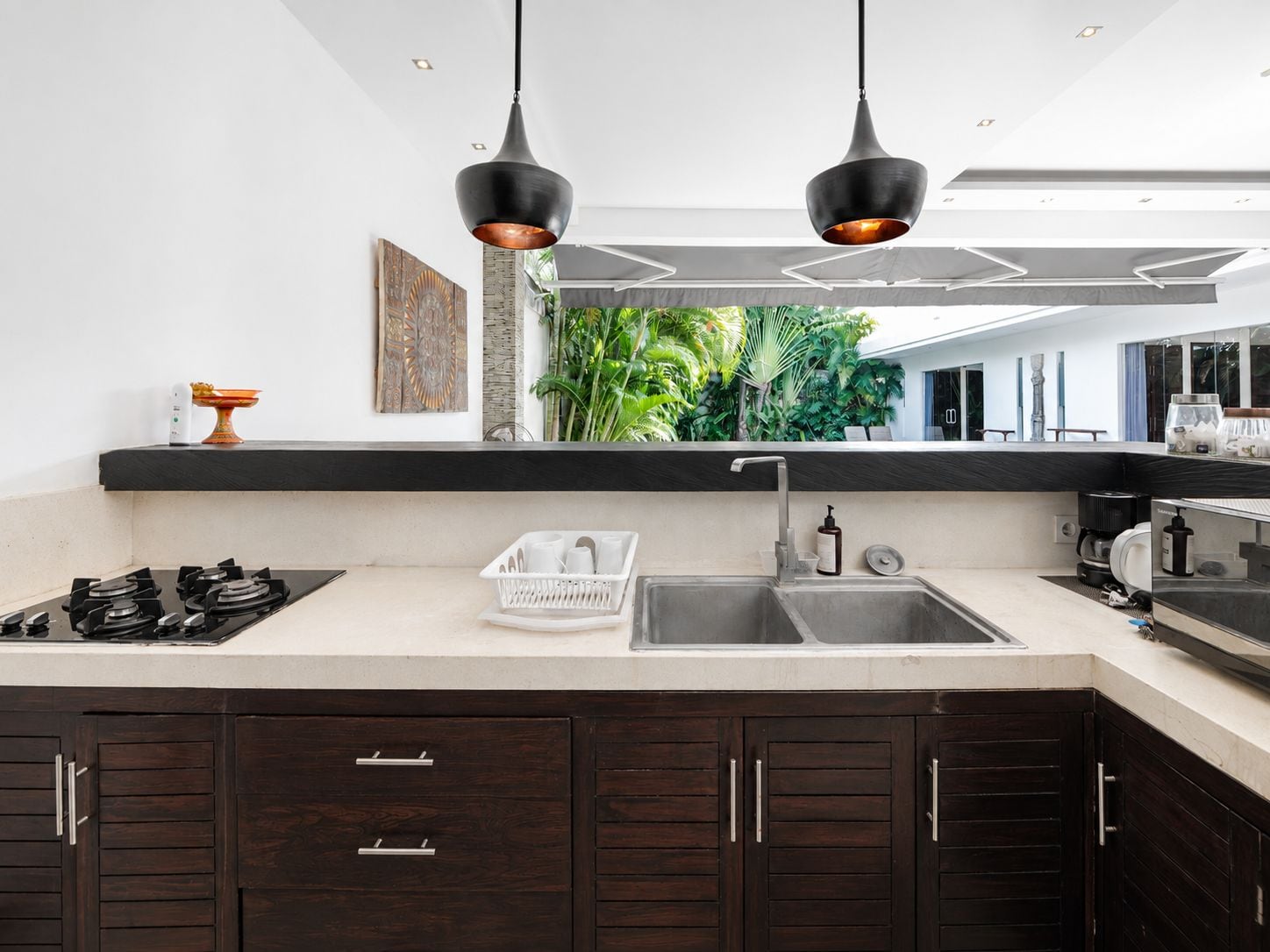 A modern kitchen with a gas stove, a sink, and two pendant lights.