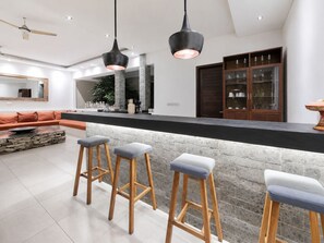 A modern kitchen with a stone island, bar stools, pendant lighting, and a built-in wine cabinet. - Villa Juna Serene 3BR Hideaway Seminyak (Seminyak)