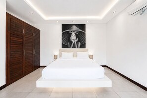 A modern bedroom with a large bed, a wardrobe, and a wall-mounted artwork. - Villa Juna Serene 3BR Hideaway Seminyak (Seminyak)