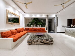 Una sala de estar moderna con un sofá modular, una mesa de centro de piedra y un ventilador de techo.
