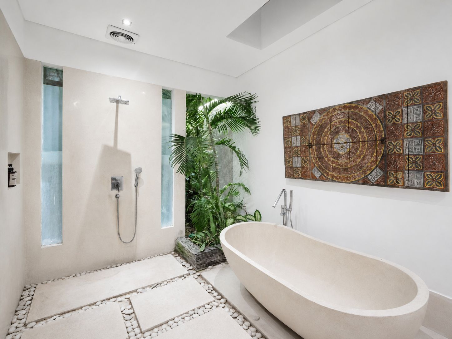 A modern bathroom with a freestanding bathtub, a shower with a glass enclosure, and a decorative tile wall.
