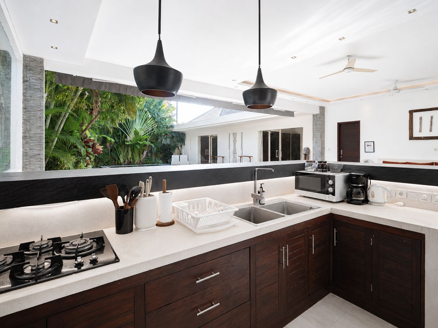 A modern kitchen with a gas stove, a microwave, a coffee maker, and a sink.