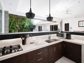 Una cocina moderna con estufa a gas, microondas, cafetera y lavabo.