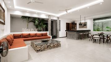 A modern living room with a stone coffee table, a sofa, and a dining area with chairs and a table.