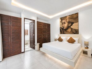 Un dormitorio moderno con una cama grande, armarios de madera y un cuadro de gran tamaño en la pared.