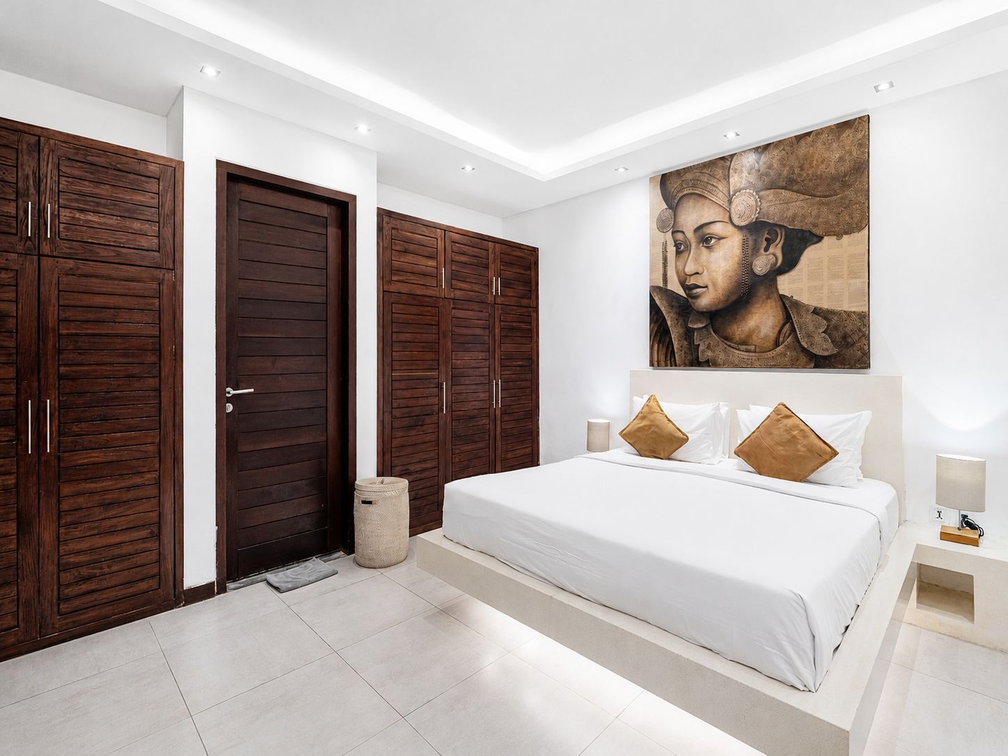 A bedroom with a large bed, wooden wardrobes, and a wall-mounted artwork.