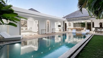 A modern house with a swimming pool, a patio area, and a well-maintained lawn.
