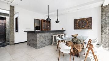Una cocina moderna con una isla central, sillas blancas y una mesa de comedor.