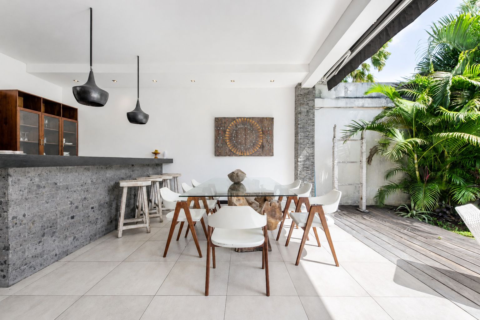 Una cocina moderna con comedor, que cuenta con encimera de piedra, sillas blancas e iluminación colgante.