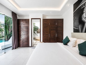 Un dormitorio moderno con una cama grande, vista a una piscina y armarios de madera.