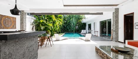 Un interno moderno con piscina, zona pranzo e cucina.