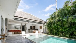 Ein modernes Haus mit Swimmingpool, Sitzgelegenheiten im Freien und üppiger Bepflanzung.